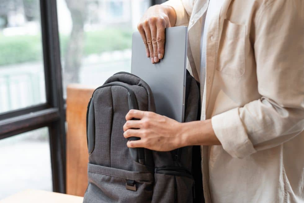 a person holding a laptop in their backpack