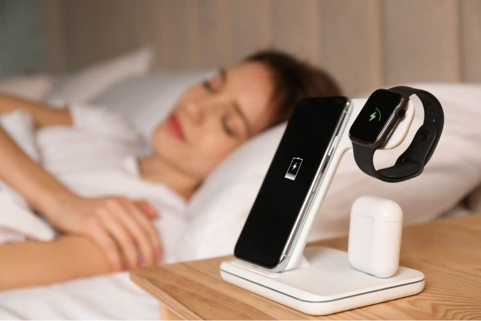 a woman sleeping in bed with a smart watch and a smartwatch